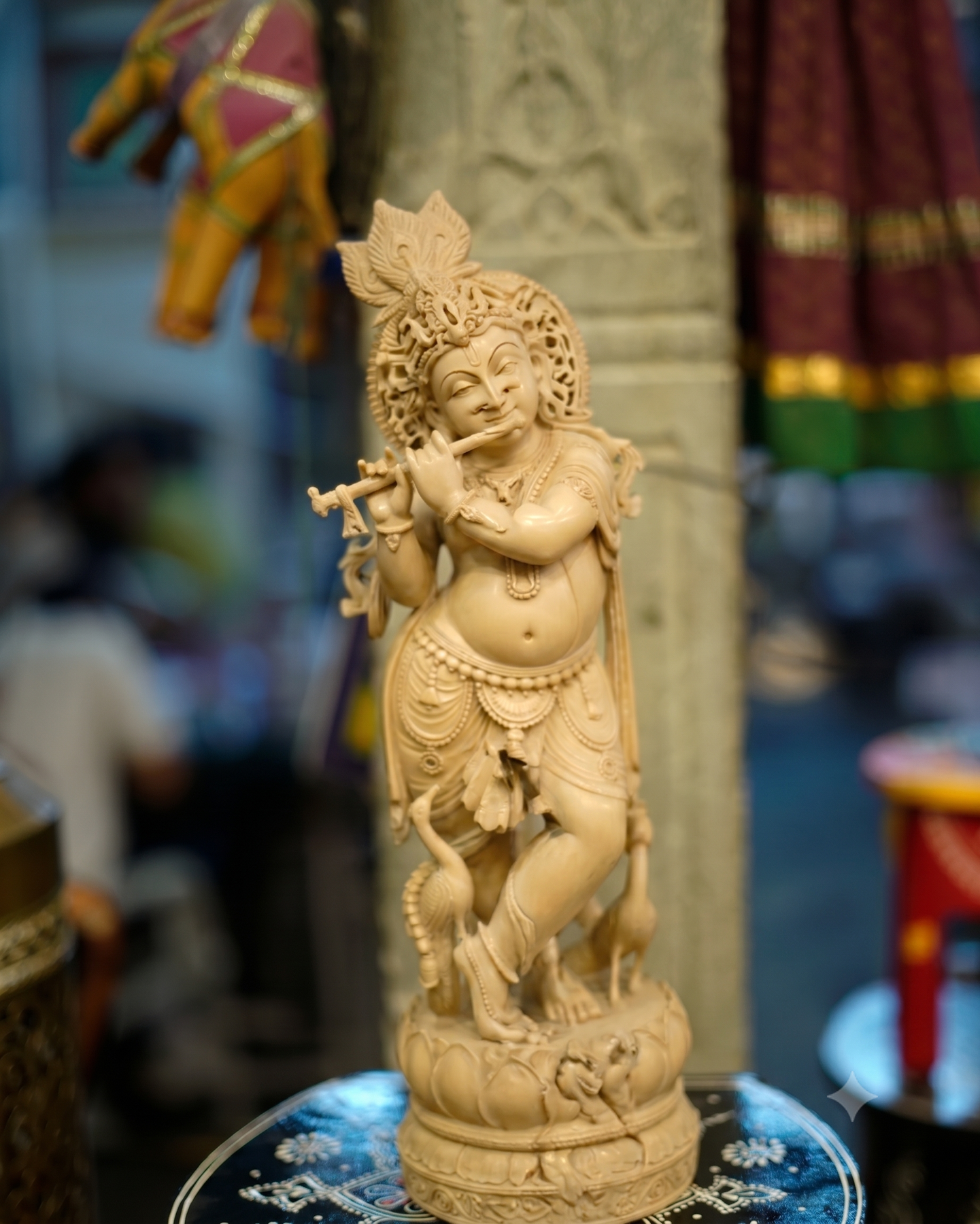 A finely carved wooden Krishna playing the flute, standing on a lotus base